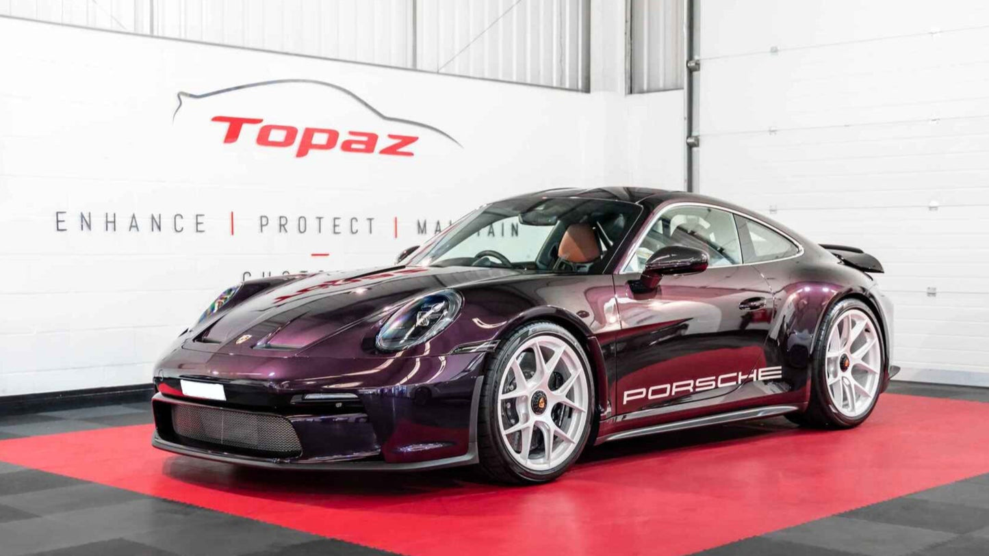 Purple Porsche 911 st car in a showroom with Topaz branding.